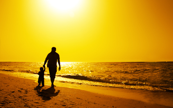 Father and kids silhouettes on the beach at sunset - Foto, Bild