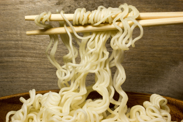 Στιγμιαία noodles σε ένα ξύλινο μπολ με chopsticks. Ξύλο παρασκήνιο. - Φωτογραφία, εικόνα