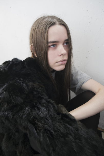 girl in a black coat against a white wall - Φωτογραφία, εικόνα