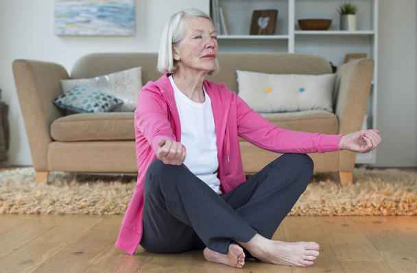 Elderly lady meditating at home - Photo, image