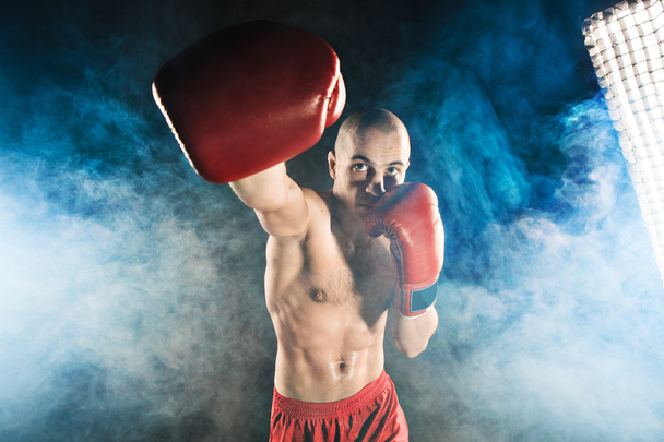 The young man kickboxing in blue smoke - Photo, Image