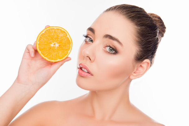 Pretty healthy girl holding half of orange near her face - Foto, Bild