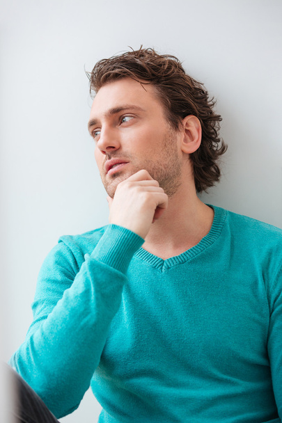 Curly pensive young man thinking and looking at the window  - 写真・画像