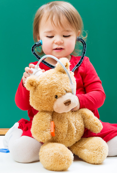 meisje zorg voor haar teddy beer met een stethoscoop - Foto, afbeelding
