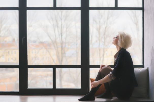 Portrét zasněné dívky. Sedí na okenním parapetu. - Fotografie, Obrázek