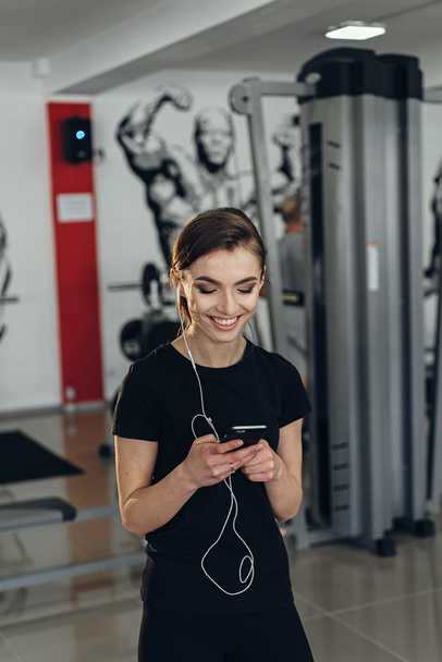 Beautiful girl in the gym with your phone - Фото, изображение