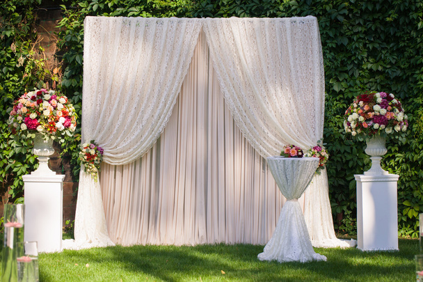 весільна арка з великими квітковими букетами на зеленому листі
 - Фото, зображення