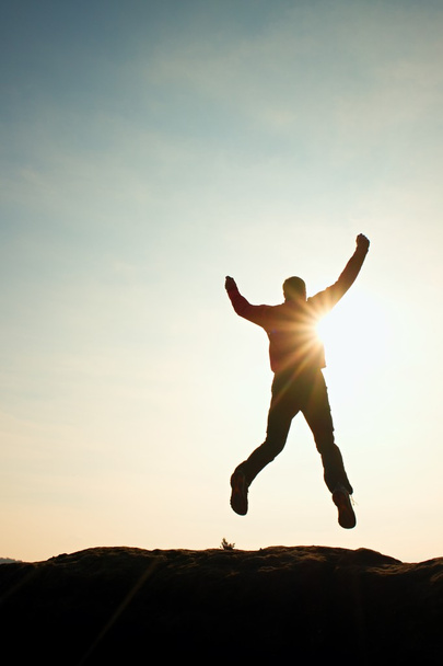 Jumping man. Gek jongeman is springen op kleurrijke hemelachtergrond. Silhouet van jumping man en mooie avondrood. - Foto, afbeelding