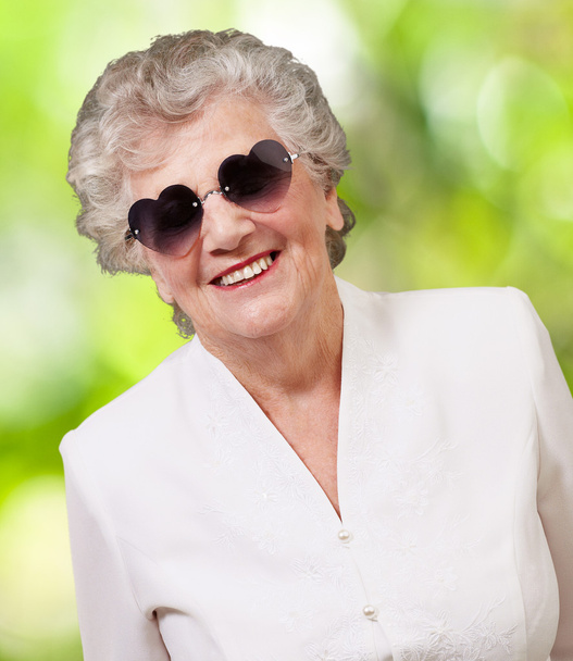 Ritratto di donna anziana felice che indossa occhiali di cuore contro una n
 - Foto, immagini