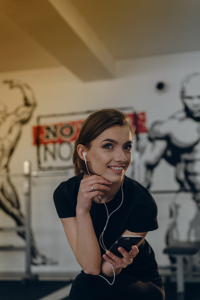 Beautiful girl at the gym listening to music - Photo, image