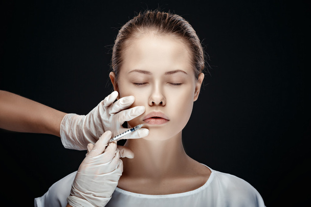 Portrait of young Caucasian woman getting cosmetic injection - 写真・画像
