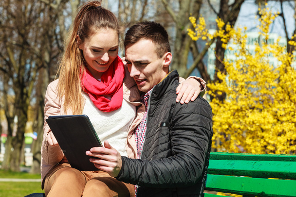 couple with  tablet sitting on bench - Valokuva, kuva