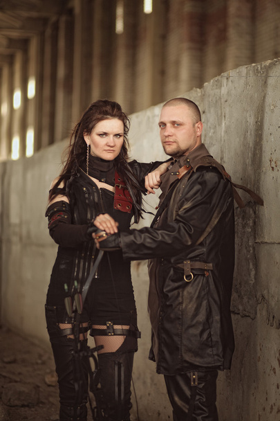 Tribal couple in leather costume with a bow inside abandoned building - Foto, Bild