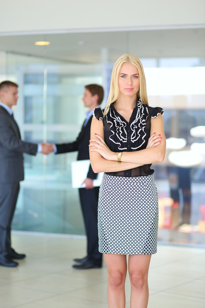 Portrait of young businesswoman in office with colleagues in the background - Foto, immagini