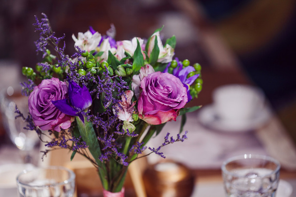 Composición de flores en restaurante, rosas e iris, tonos combinados de púrpura
 - Foto, imagen
