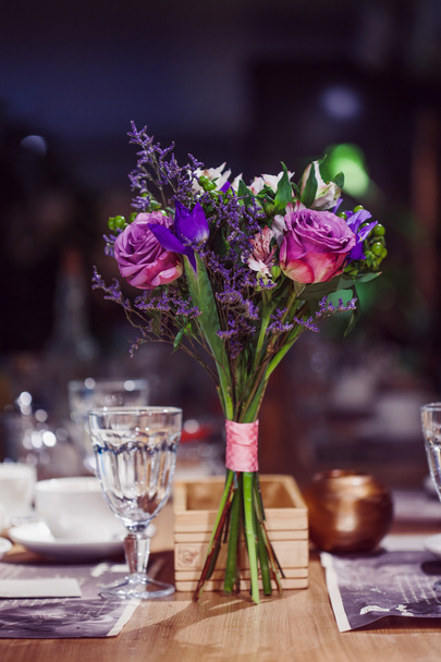 Bloemen samenstelling in restaurant, rozen en irissen, combinatie tinten paars - Foto, afbeelding