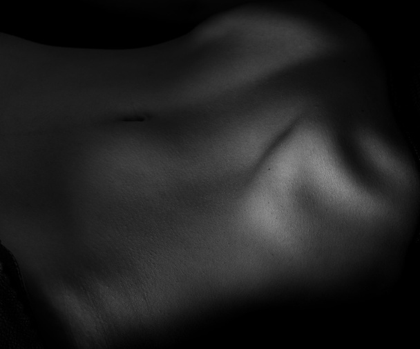 Naked belly on dark. - Foto, afbeelding