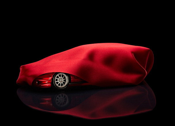 nieuwe auto verborgen onder rode kaft - Foto, afbeelding