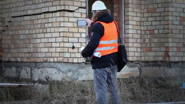 Building inspector filmed with tablet PC near the building - Video, Çekim
