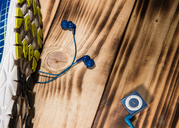 Running shoes and mp3 player on a wooden floor background - Fotó, kép