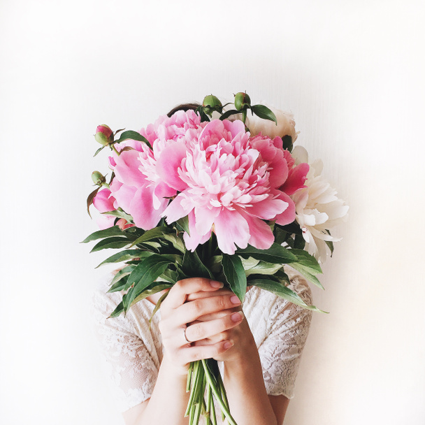 Fille avec bouquet de pivoines roses au mur blanc - Photo, image