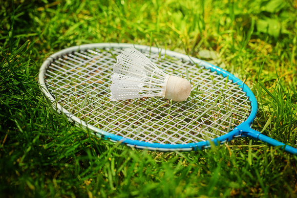 Shuttlecock and badminton racket on green grass. - Foto, afbeelding