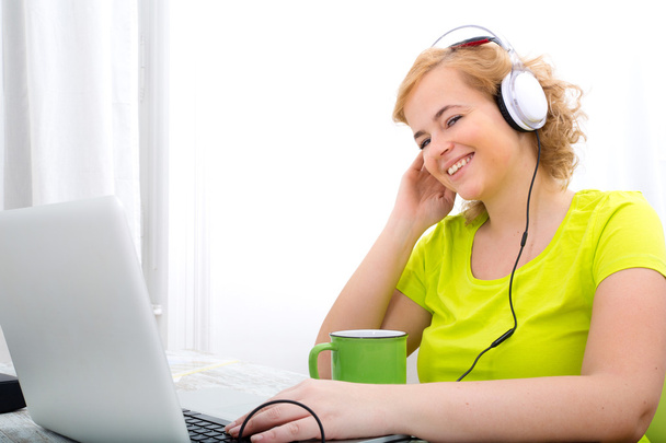 Young plus size woman listening to Audio while working on a lapt - Photo, image