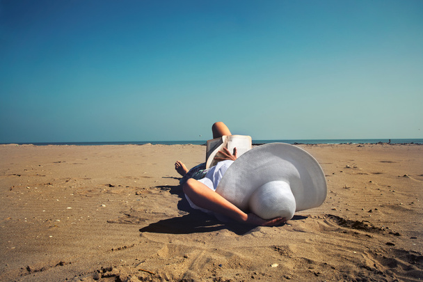 Расслабленная женщина, читающая книгу на берегу моря
 - Фото, изображение