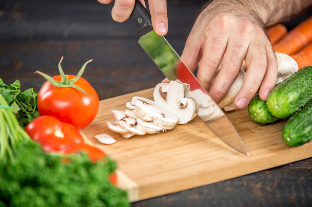 Чоловічі руки ріжуть овочі для салату
 - Фото, зображення