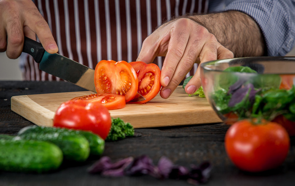 Mani maschili che tagliano verdure per insalata
 - Foto, immagini