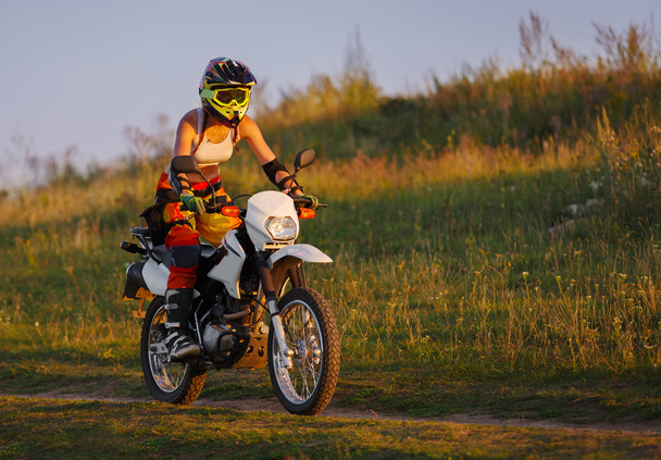 Kobieta rowerzysta w zachód słońca, kobiece motocykl. - Zdjęcie, obraz