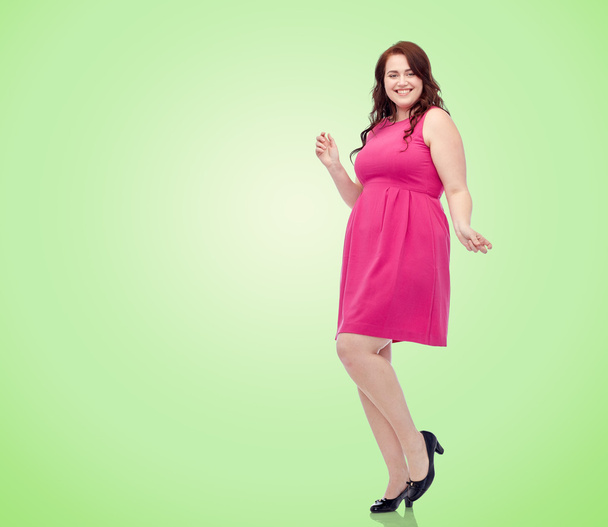 happy young plus size woman dancing in pink dress - 写真・画像