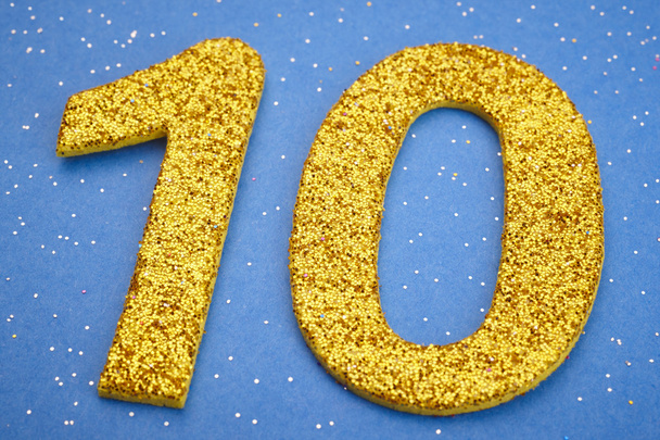 Número diez de color amarillo sobre fondo azul. Aniversario
 - Foto, imagen