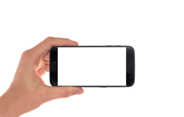 Moderno smart phone nero in mano all'uomo in posizione orizzontale. Schermo bianco per mockup, isolato
. - Foto, immagini