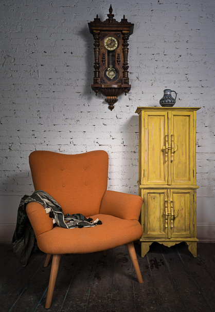 Vintage πορτοκαλί πολυθρόνα, κίτρινο ντουλάπι, ρολόι εκκρεμές και μαύρο κασκόλ - Φωτογραφία, εικόνα