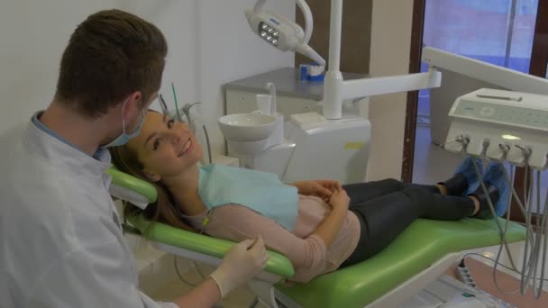 Dentist is Talking to a Client Gives Her a Mirror Woman is Smiling Looking at the Mirror Doctor is Sitting Behind a Patient's Head Dental Clinic - Filmati, video