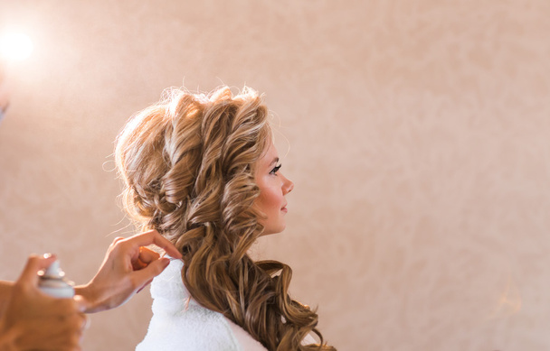 Hochzeit Make-up Artist macht ein Make-up für Braut. schöne sexy Modell Mädchen drinnen. Schönheit blonde Frau mit lockigem Haar. Hände in der Nähe des Gesichts - Foto, Bild