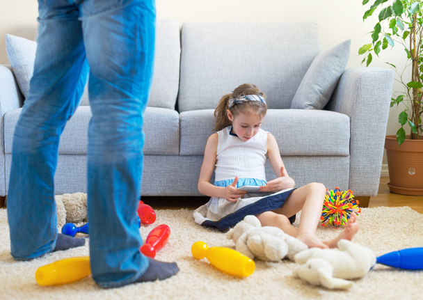 Es ist Zeit, Ihr Spielzeug aufzuräumen! kleines Mädchen spielt mit Tablet-PC und ignoriert ihren Vater. - Foto, Bild