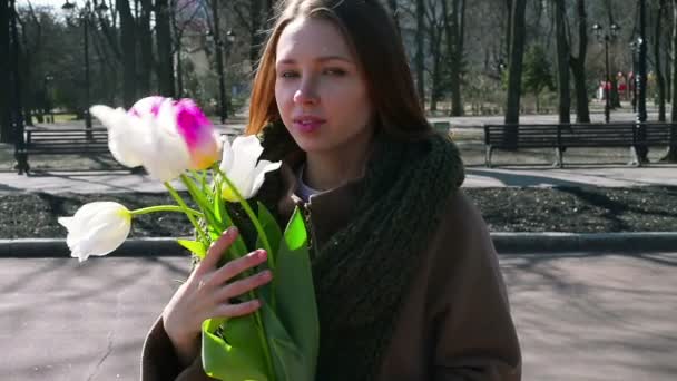 Frau steht im Park und hält weißen Strauß in der Hand - Filmmaterial, Video