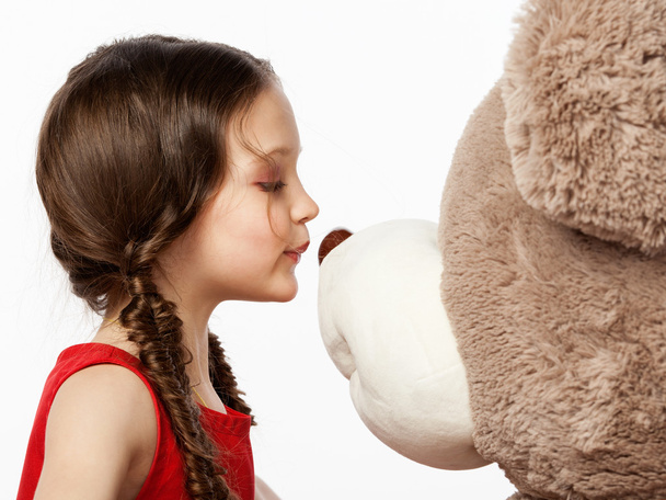 Portrait of a little brunette girl kissing a teddy bear into it' - Fotó, kép