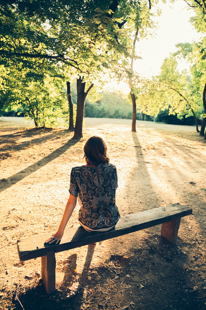 Девушка сидит на скамейке в парке - Фото, изображение