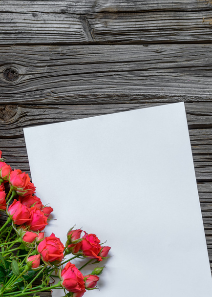 Papier blanc sur surface en bois avec faisceau de roses
 - Photo, image