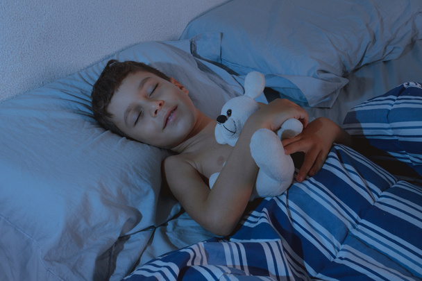 寝室でテディベアと眠る少年の肖像画 - 写真・画像