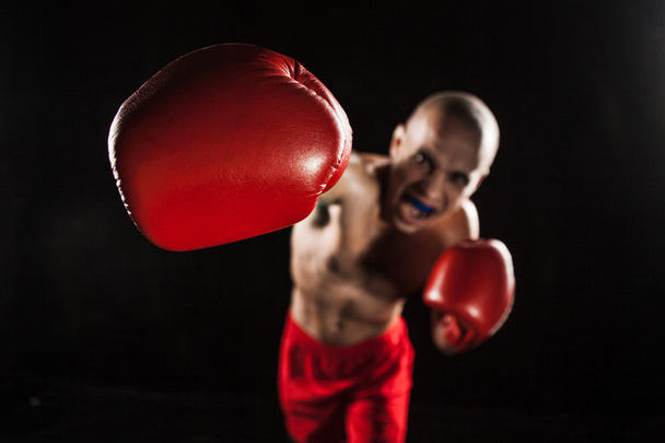 der junge Mann kickboxt auf schwarz mit Kapa im Mund - Foto, Bild