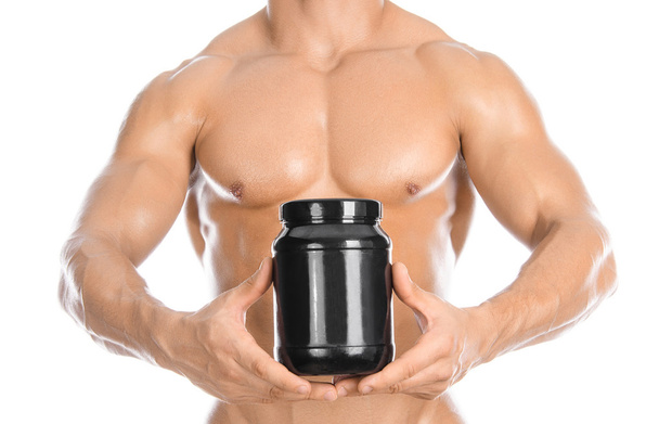 Bodybuilding and Sports theme: handsome strong bodybuilder holding a plastic jar with a dry protein and showing gesture isolated on white background in studio - Foto, Imagem