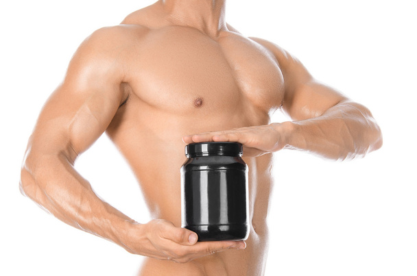 Bodybuilding and Sports theme: handsome strong bodybuilder holding a plastic jar with a dry protein and showing gesture isolated on white background in studio - Фото, изображение