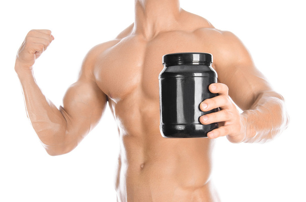 Bodybuilding and Sports theme: handsome strong bodybuilder holding a plastic jar with a dry protein and showing gesture isolated on white background in studio - Valokuva, kuva
