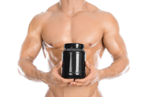 Bodybuilding and Sports theme: handsome strong bodybuilder holding a plastic jar with a dry protein and showing gesture isolated on white background in studio - Photo, Image