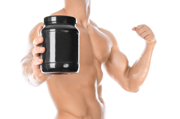 Bodybuilding and Sports theme: handsome strong bodybuilder holding a plastic jar with a dry protein and showing gesture isolated on white background in studio - Foto, afbeelding