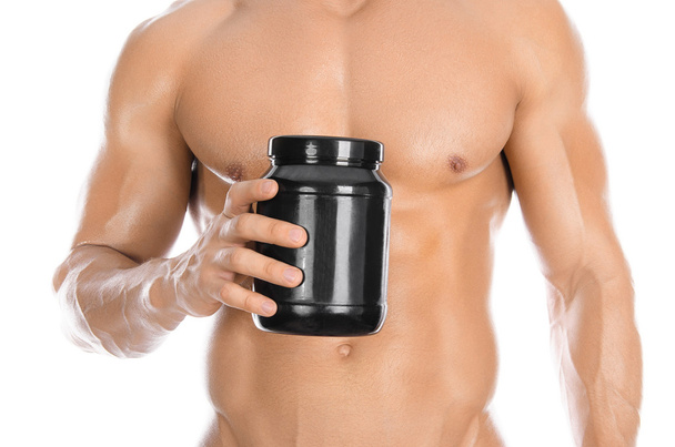 Bodybuilding and Sports theme: handsome strong bodybuilder holding a plastic jar with a dry protein and showing gesture isolated on white background in studio - Foto, Bild